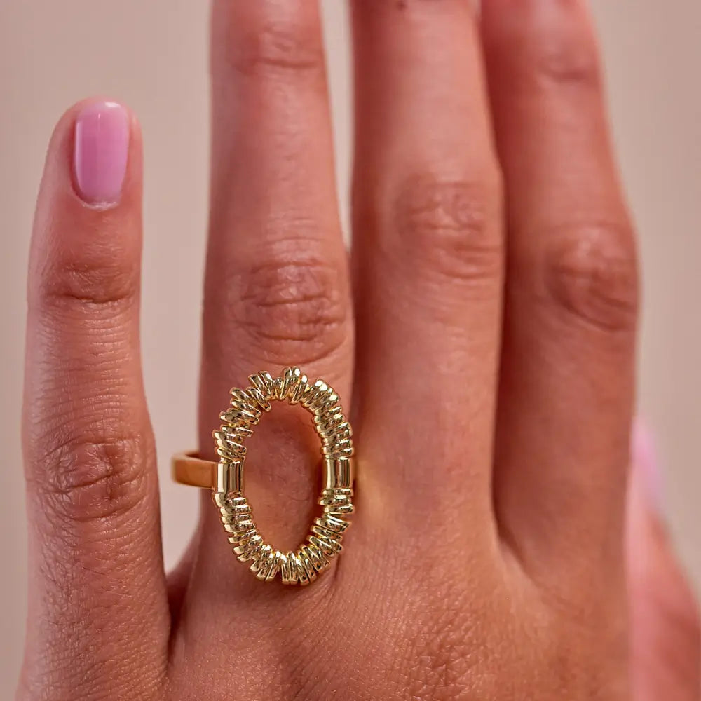 Woman wearing a gold open oval statement ring with textured detail by Julie Saldivia